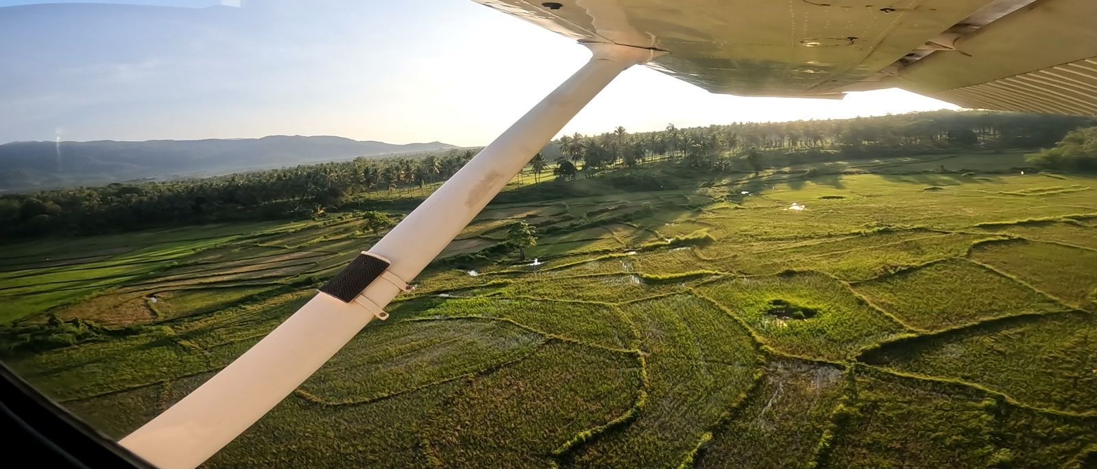 View from a high-wing aircraft over green fields
